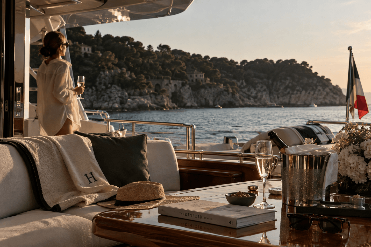 The aft deck of a yacht anchored off a wooded coastline in the evening